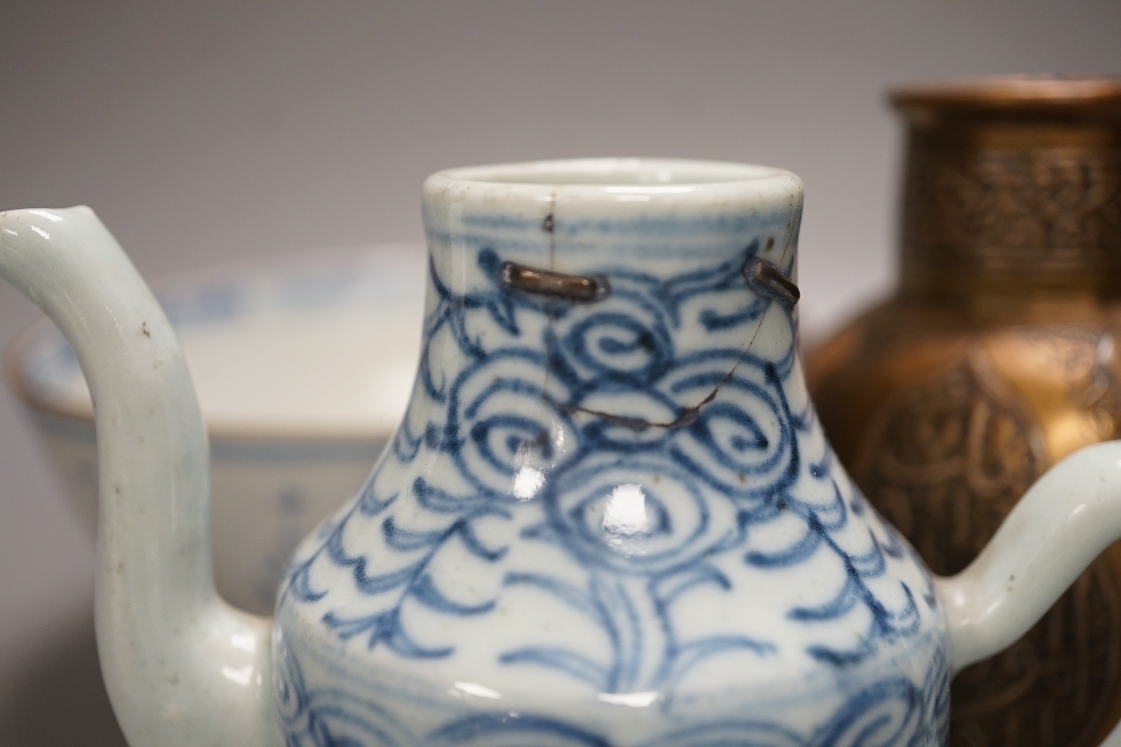 A Chinese Ming dynasty internally decorated porcelain tea bowl, an 18th century blue and white bowl, two other blue and white bowls, a similar water pot and an Islamic brass vessel